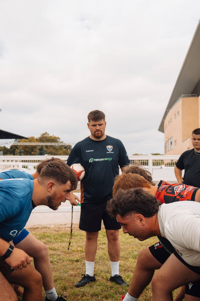 Rugby players and coach prepare for a match at an outdoor training session in Budapest.